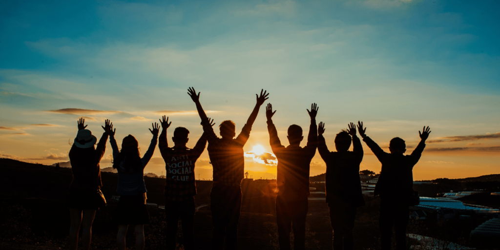 Grupo de jovenes saltando de alegria apreciando la vida frente a un atardecer