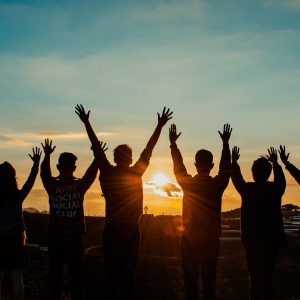 Grupo de jovenes saltando de alegria apreciando la vida frente a un atardecer